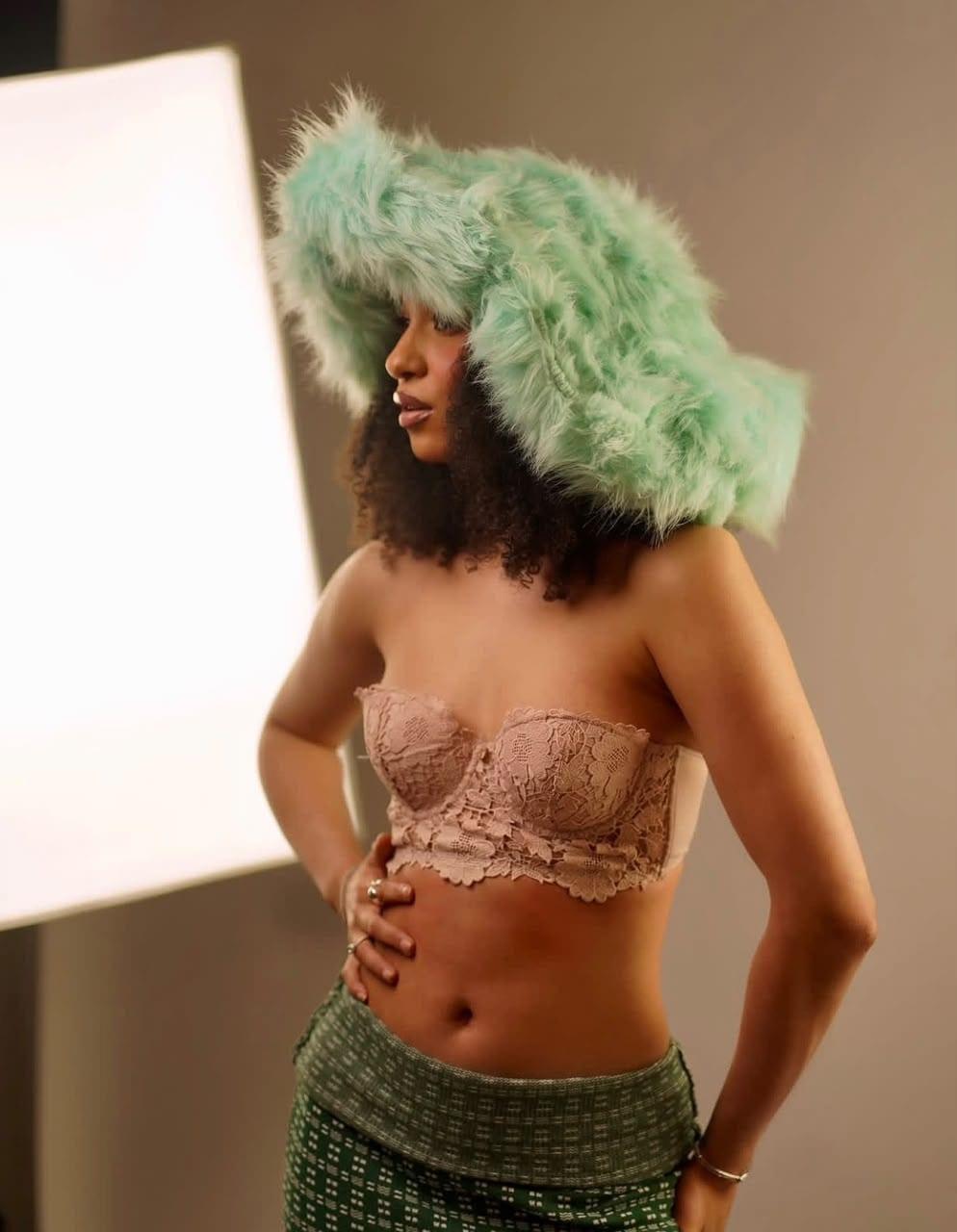 Sage lace bralette styled with a moss-green skirt, backlit editorial