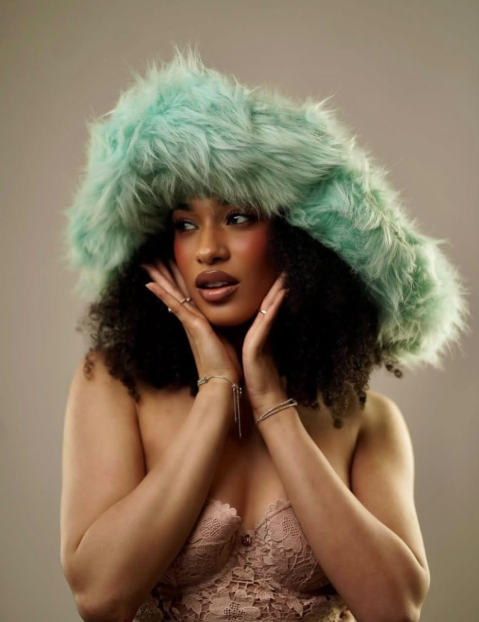 Close portrait in a mint faux fur hood and blush lace bralette